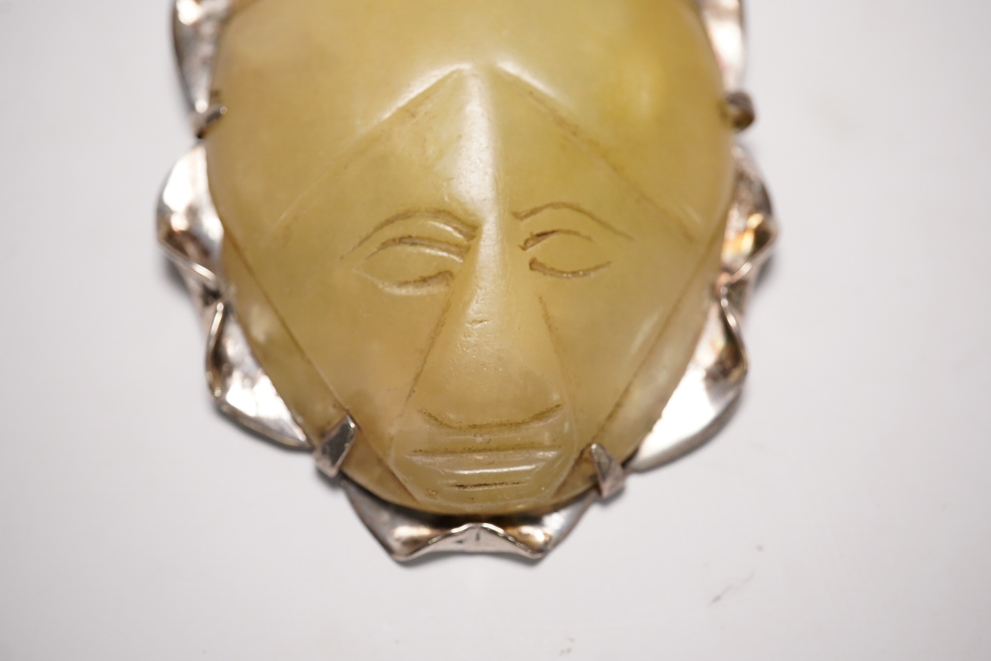 A Mexican silver mounted jadeite brooch, the jadeite face possibly pre-Columbian, 6cm high. Condition - fair, chip to top of brooch